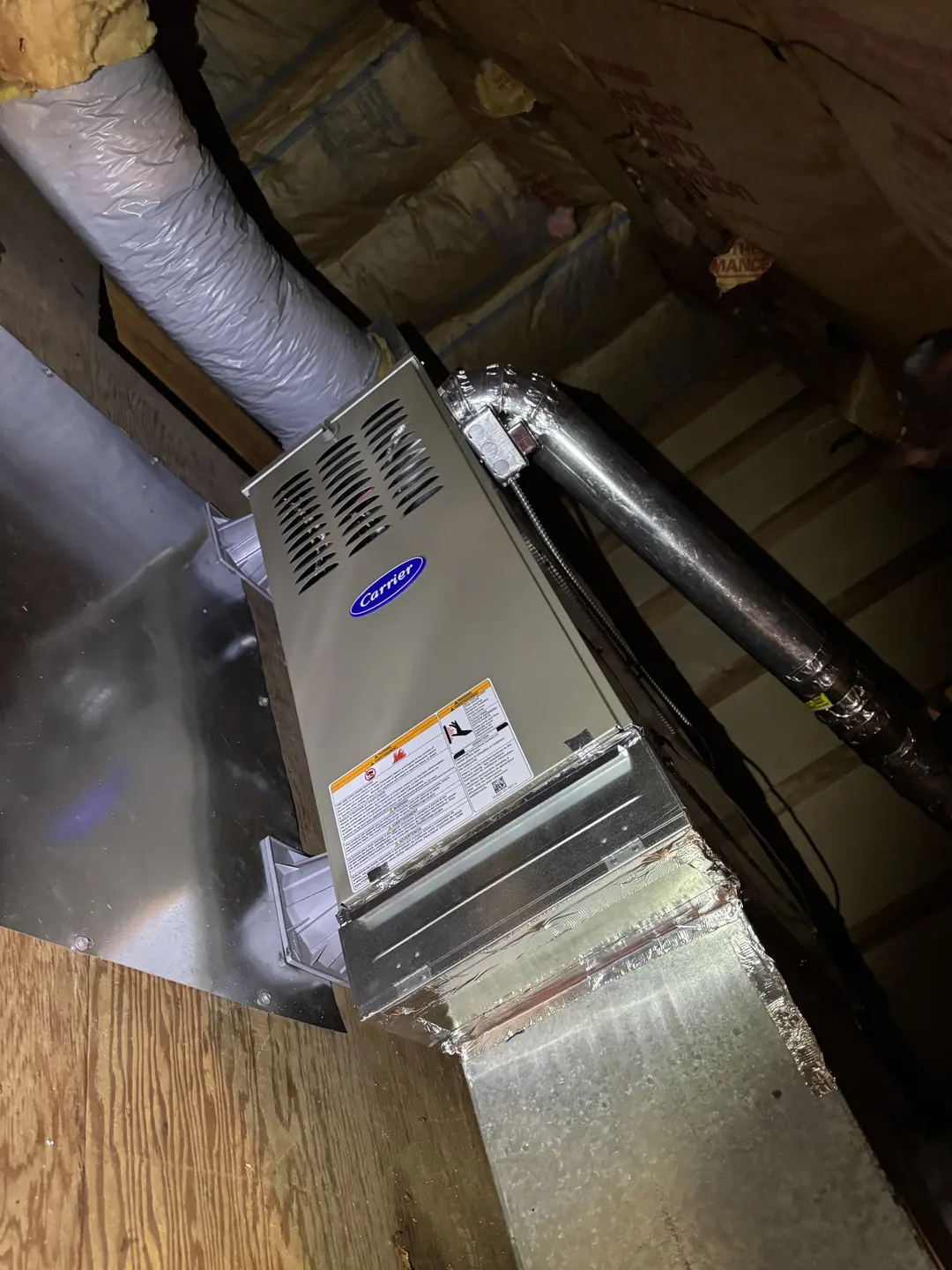 Close-up of a newly installed Carrier residential furnace label and rating plate inside a West Los Angeles mechanical space