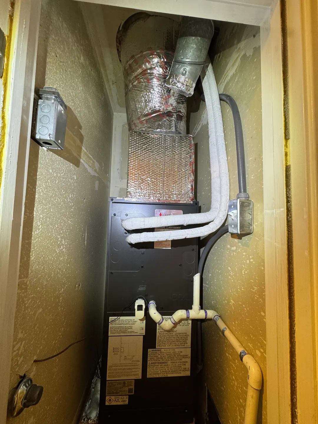 Mitsubishi air handler with insulated refrigerant lines and PVC condensate piping installed in a tight West Los Angeles closet ceiling cavity