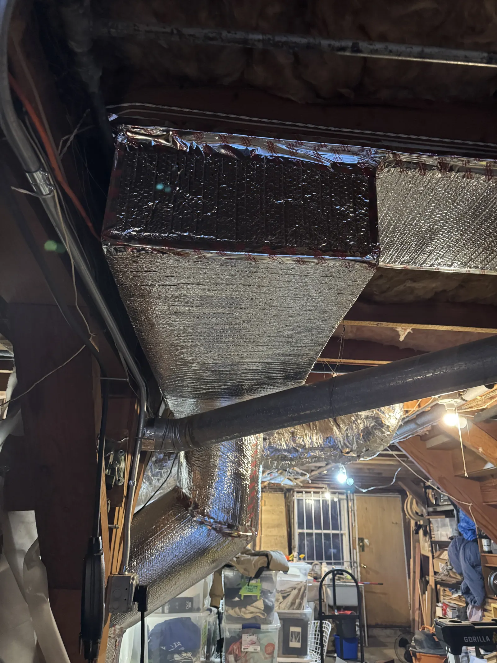 Newly installed insulated supply plenum drop with sheet metal transition and reflective wrap in a West Los Angeles utility room
