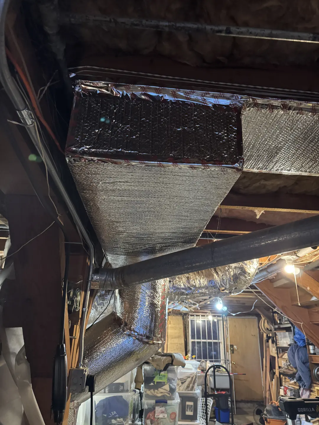 Newly installed insulated supply plenum drop with sheet metal transition and reflective wrap in a West Los Angeles utility room