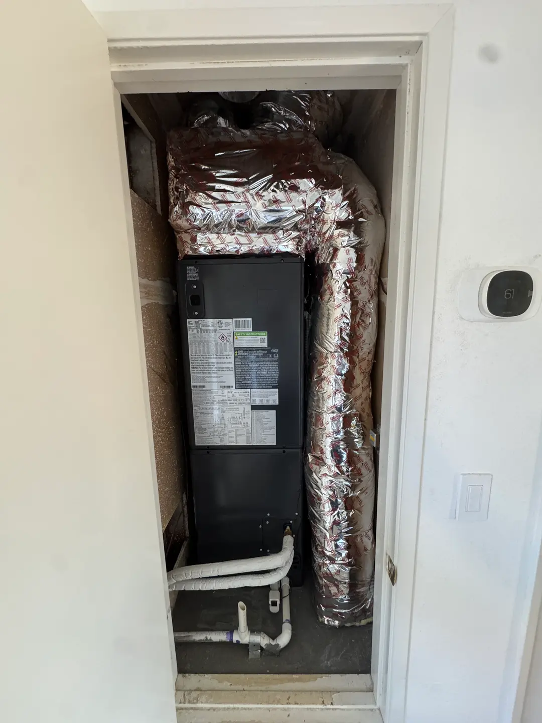 Goodman vertical air handler installed inside a clean West Los Angeles mechanical closet with new flex-duct supply and PVC condensate routing