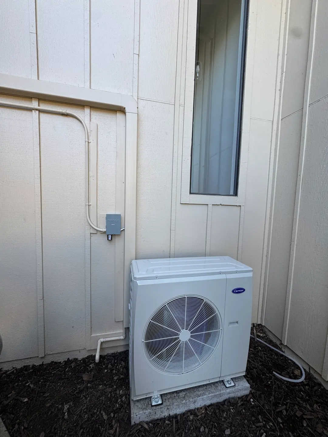 Carrier outdoor heat pump on a side-yard pad of a West Los Angeles single-family home with conduit running back to the panel