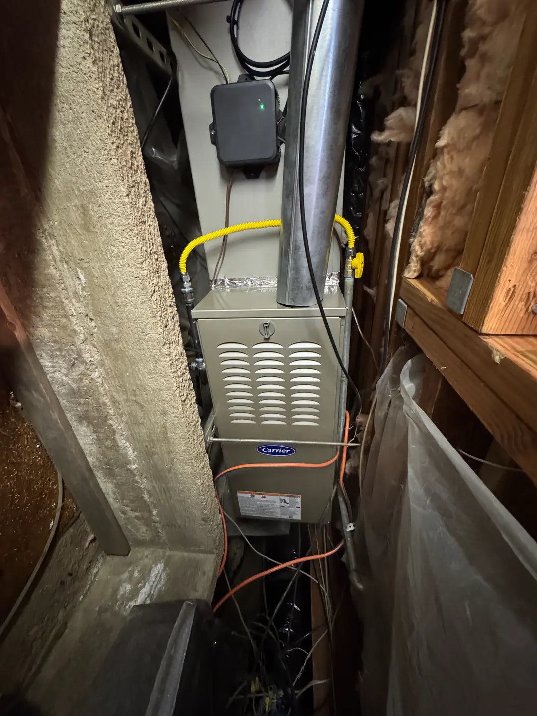 Carrier 80% gas furnace installed in a Bel-Air crawl-space pad with corrugated stainless gas line and AC disconnect mounted overhead