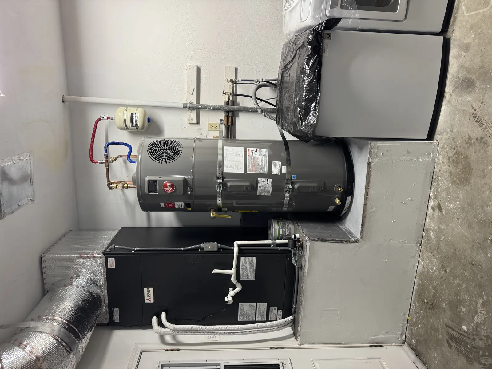 Top view of a newly installed Rheem electric water heater with copper trim, expansion tank, and seismic strapping in a West Los Angeles utility room