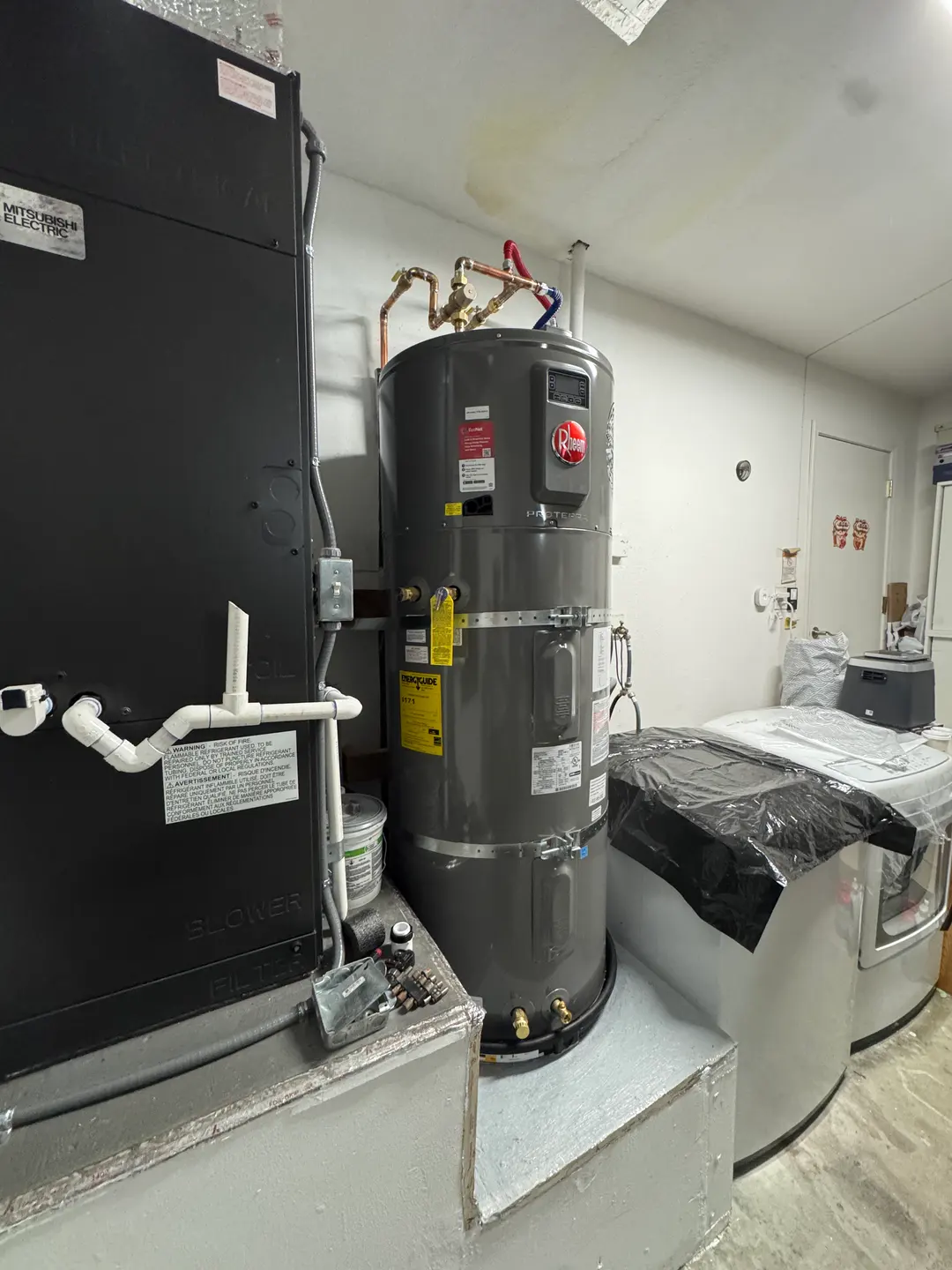 Mitsubishi Electric vertical air handler with seismic strapping and PVC condensate piping installed in a West Los Angeles mechanical room
