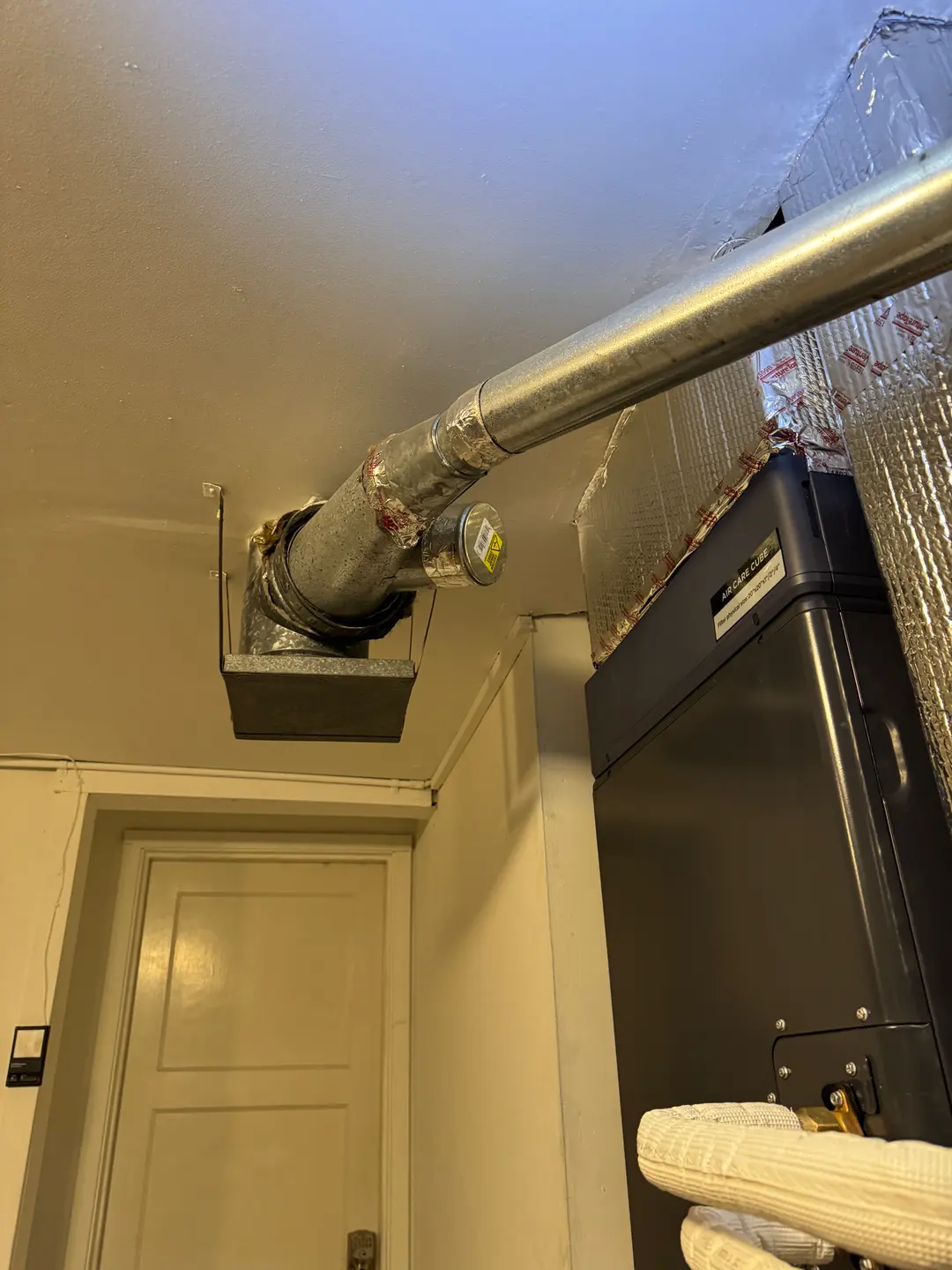 Indoor air handler with insulated supply plenum and B-vent through the ceiling of a West Los Angeles utility space