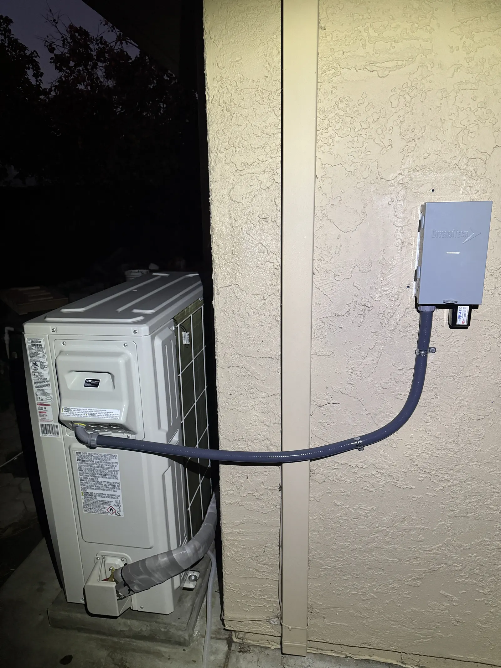 Mitsubishi Electric mini-split outdoor unit with side-wall electrical disconnect and clean line-set conduit on a stucco wall in West Los Angeles